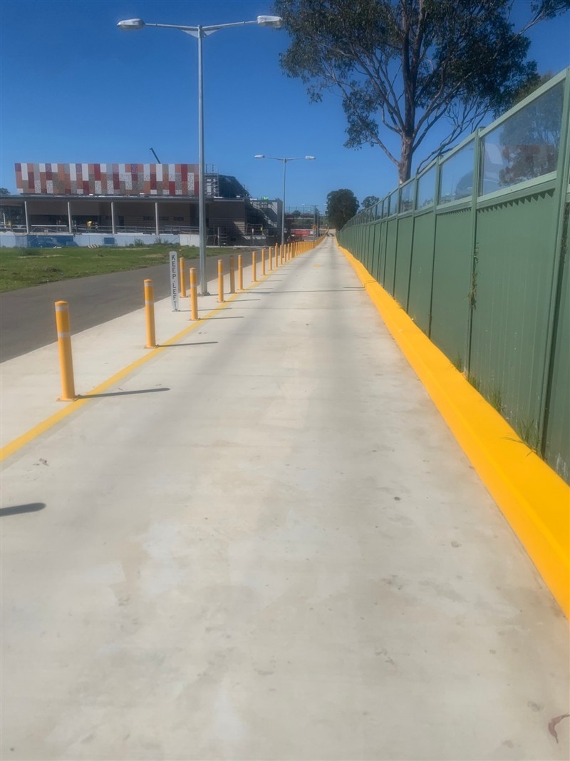 Yellow bollards and kerb highlighting along a pedestrian path