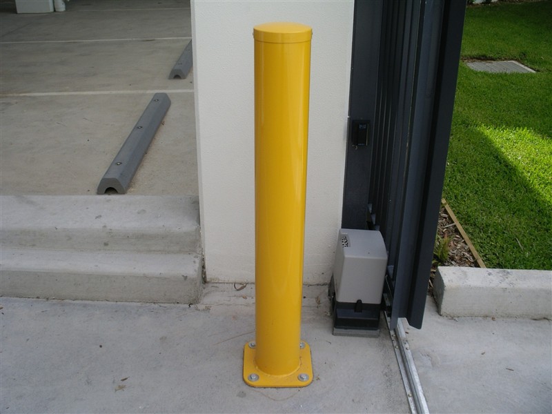 Fixed steel bollard protecting a gate motor