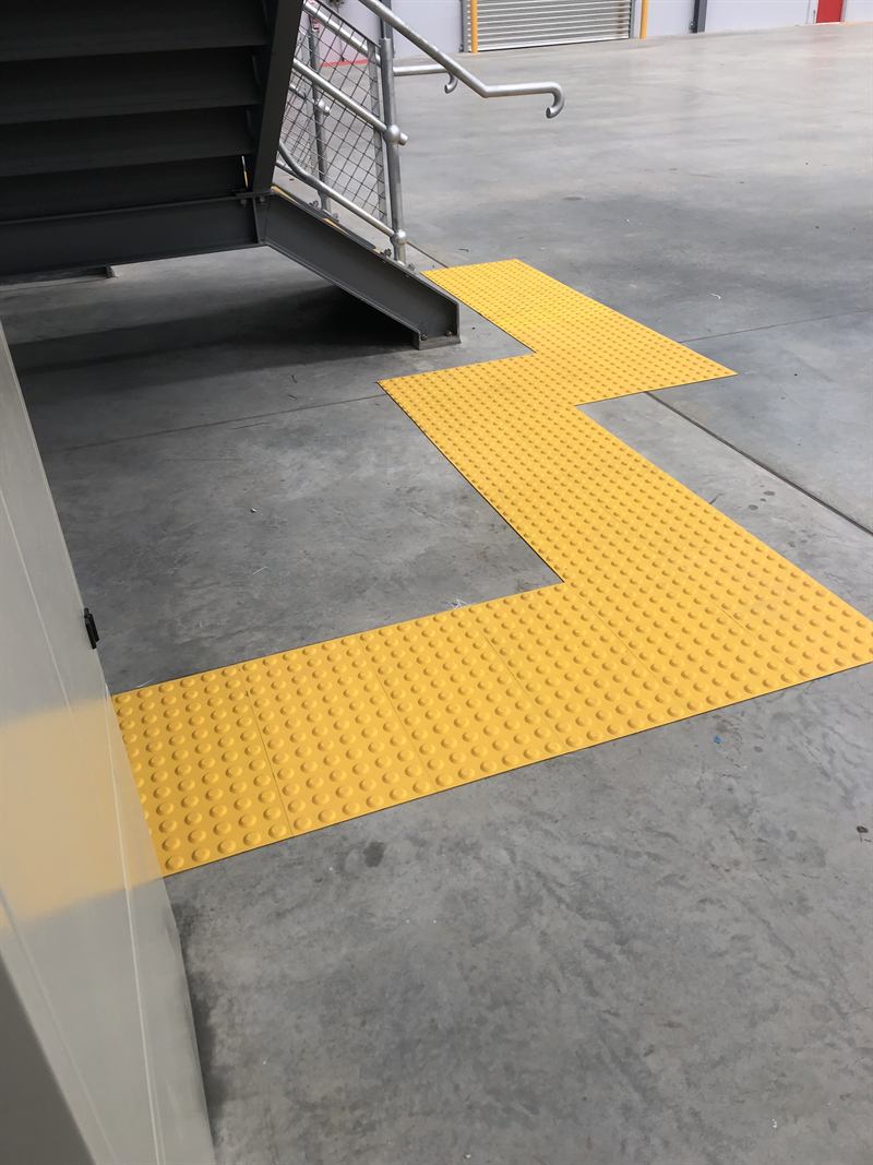Yellow tactile indicators at the foot of a staircase