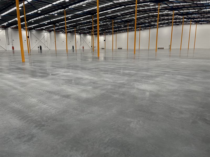 Huge glossy sealed warehouse floor reflecting the roof