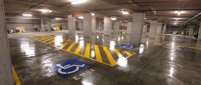 Basement carpark with yellow hatching and blue accessible bays, linemarked then sealed to a gloss