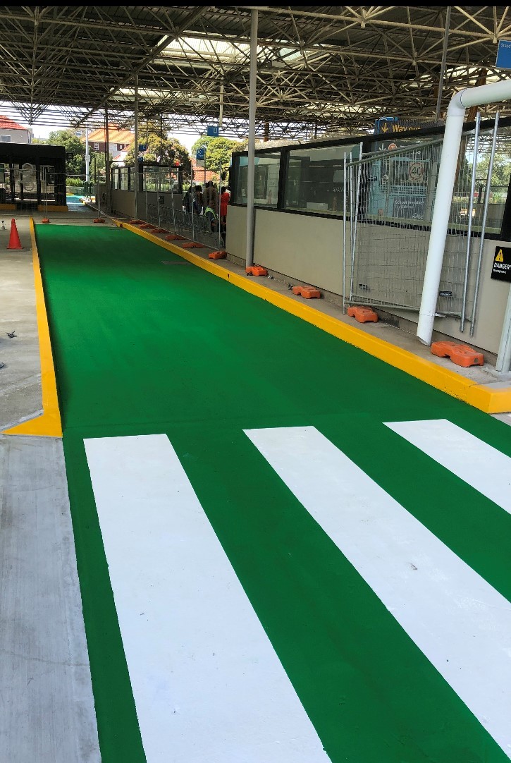 Green bus lane with white pedestrian crossing and yellow kerbs