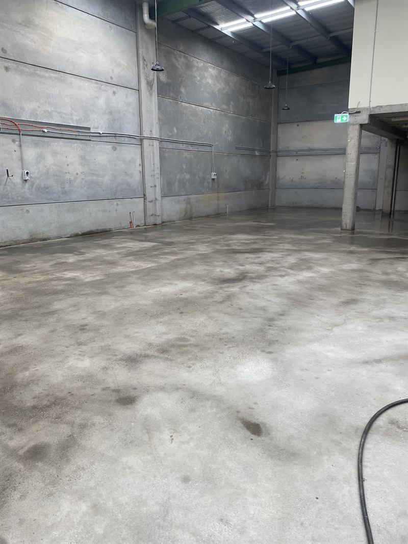 Grime along a warehouse wall before pressure cleaning